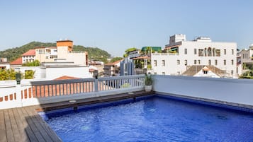 Una piscina al aire libre, sombrillas, sillones reclinables de piscina