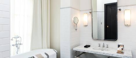 A modern bathroom with a white bathtub, a marble sink, and a large mirror above the sink.