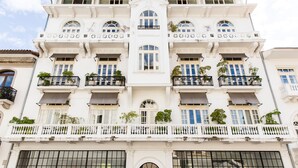 Un edificio blanco con varios balcones, ventanas amplias y barandillas decorativas.