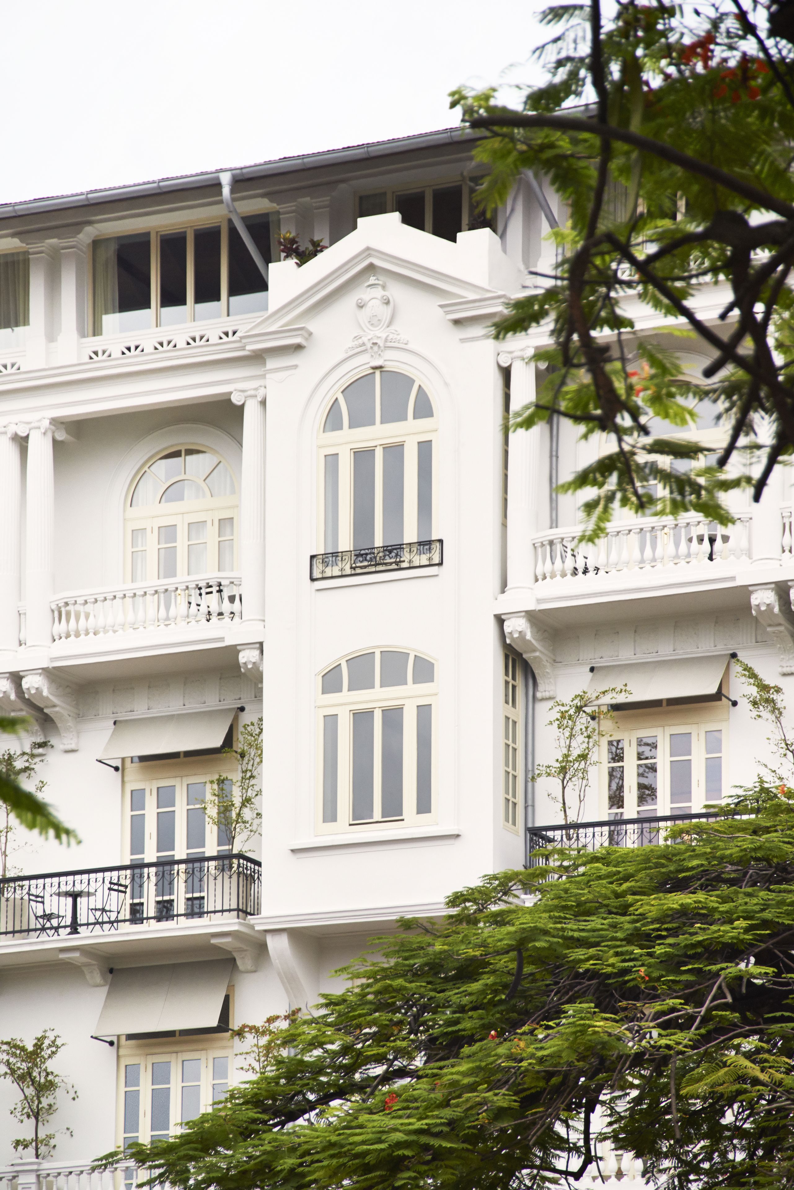 Um edifício de vários andares com paredes externas brancas, várias varandas e janelas grandes.
