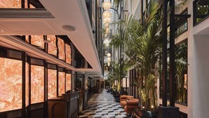 Un vestíbulo de hotel con piso a cuadros, ventanas amplias y una planta en el centro.