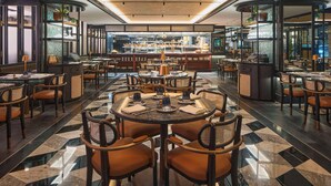 Un restaurante con mesas redondas, sillas y una zona de bar.