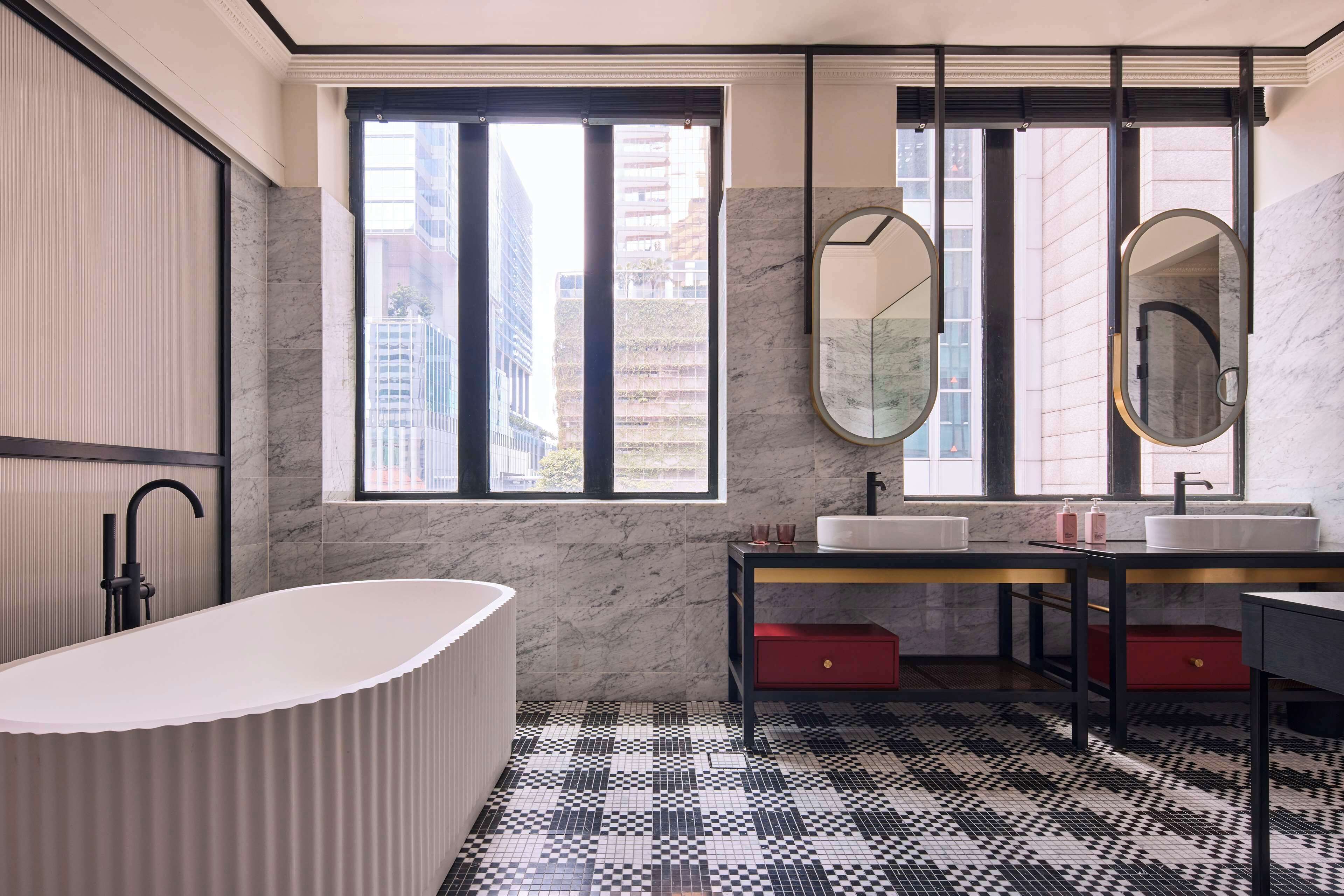 A modern bathroom with a freestanding bathtub, a double sink vanity, and a large mirror.
