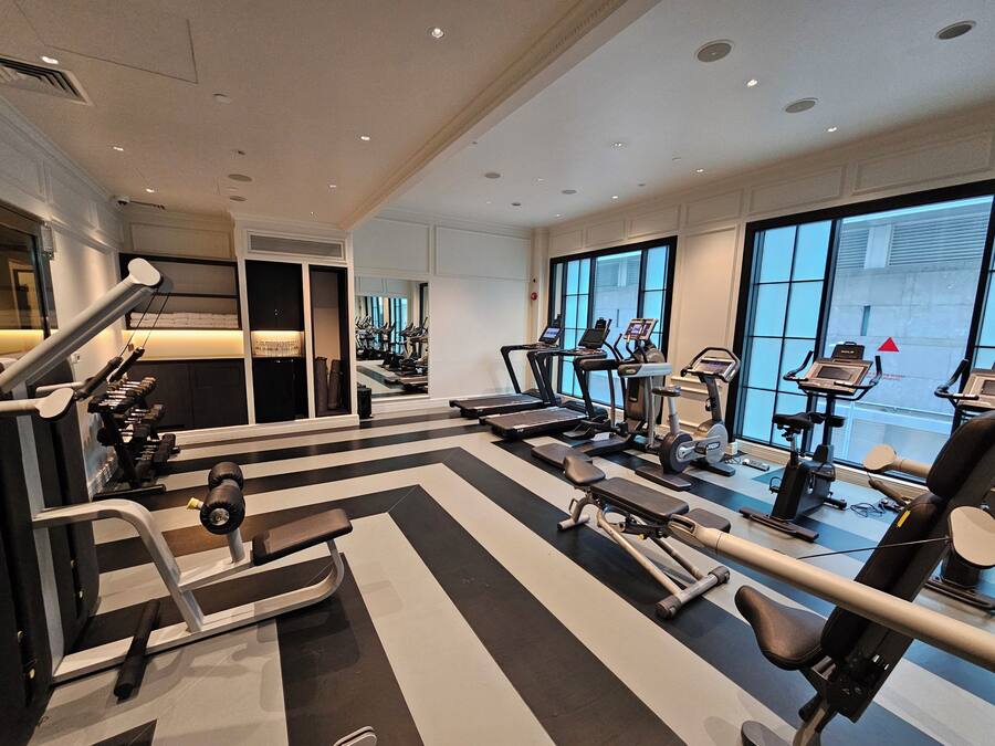 A modern gym with various exercise equipment, large windows, and a clean, well-lit interior.