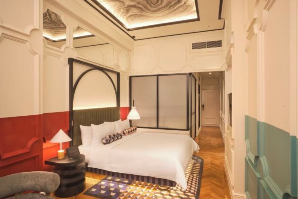 A hotel room with a bed, a nightstand, a lamp, and a patterned rug.