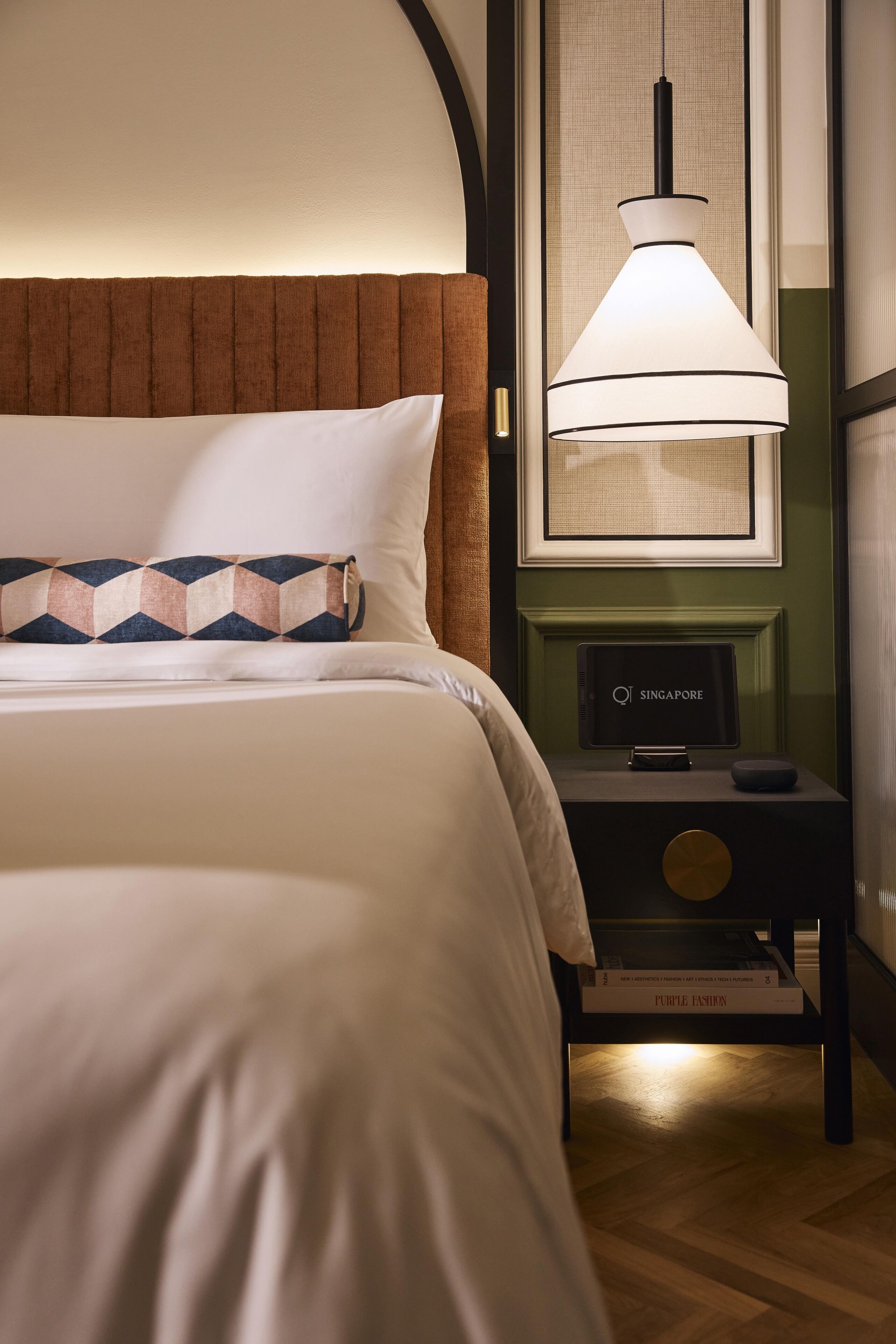 A neatly made bed with a patterned pillow, a bedside table with a lamp, and a framed picture on the wall.