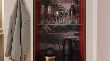 A kitchen with a built-in shelf unit containing kitchenware, a kettle, and a coffee maker.
