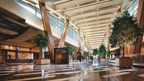 A spacious lobby with a high ceiling, large windows, and potted plants. - ARIA Sky Suites (Las Vegas)