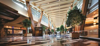 A modern hotel with a curved glass facade, a pool area with lounge chairs and umbrellas, and palm trees. at ARIA Sky Suites