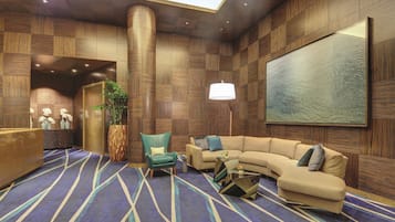 A modern lobby with a curved sofa, a reception desk, and a large abstract painting on the wall.
