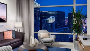 A modern living room with a city view, a sofa, a chair, a coffee table, and a potted plant. - ARIA Sky Suites (Las Vegas)
