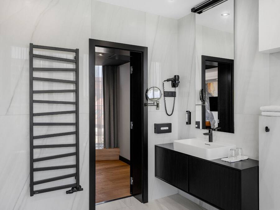A modern bathroom with a black vanity, a large mirror, and a towel rack.