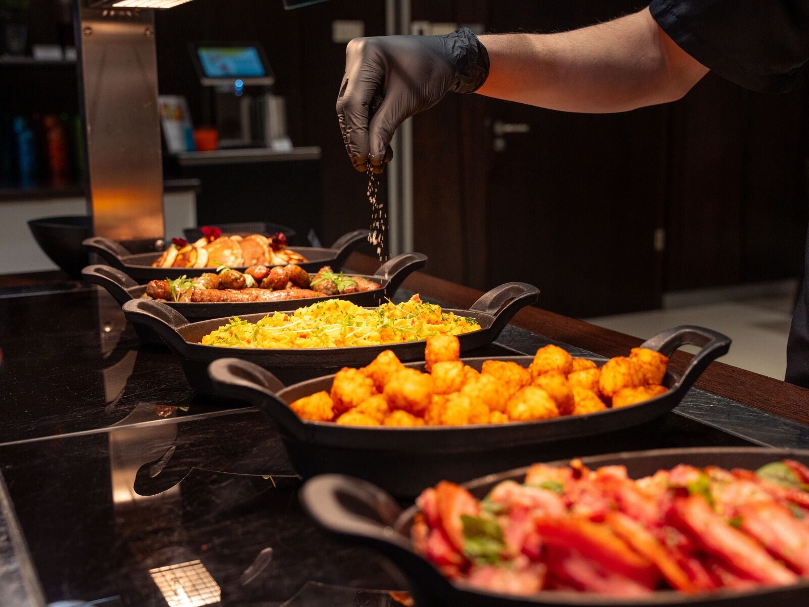 Una mesa de buffet con diversos platos en recipientes negros.
