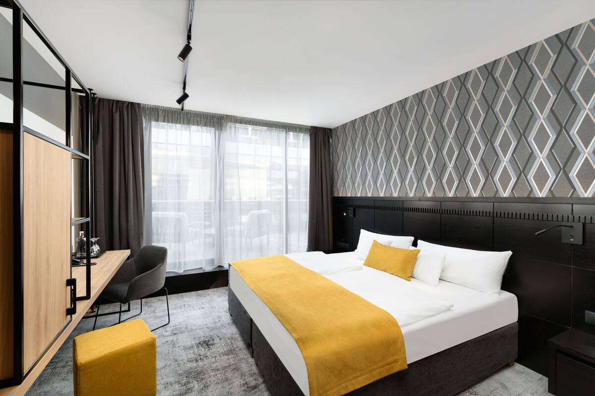 Ein modernes Hotelzimmer mit einem großen Bett, einem Schreibtisch, einem Stuhl und einem Kleiderschrank.