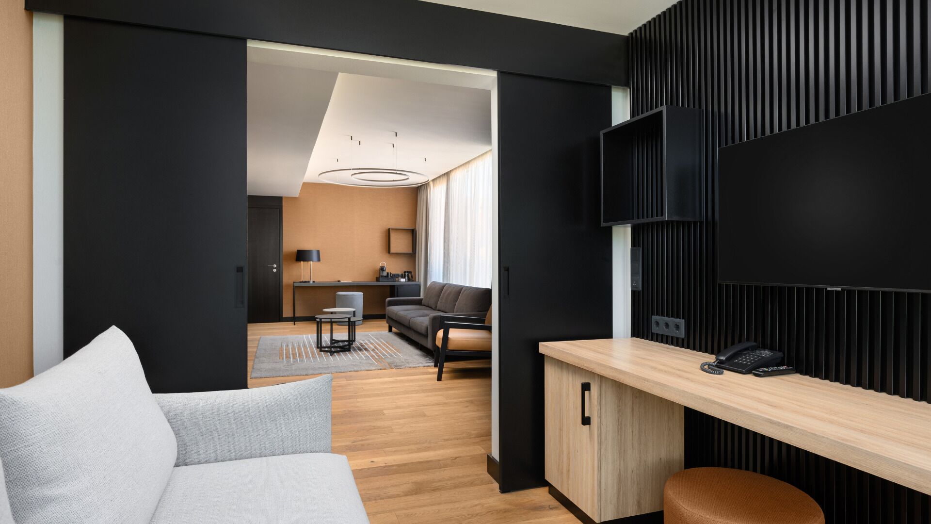 Une chambre d’hôtel moderne équipée d’un canapé, d’un bureau, d’une télévision à écran plat et offrant une vue sur la salle à manger.