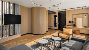 Una sala de estar moderna con una televisión de pantalla plana, detalles de madera, un sofá, una mesa de centro y una zona de comedor.