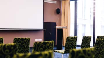 Un salón de conferencias con una pantalla de proyector, un atril y sillas estampadas.