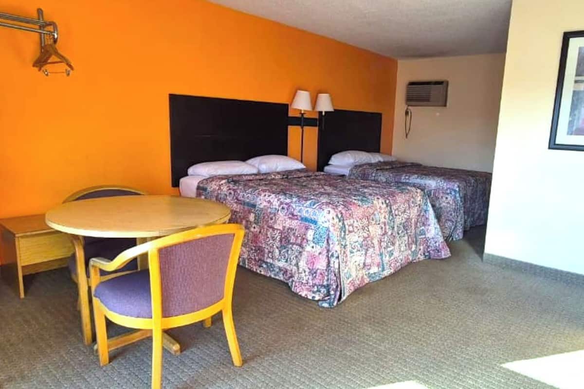 Una habitación de hotel con dos camas, una mesita y una silla.