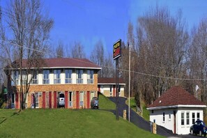 A two-story building with a red roof, a small attached garage, and a white building with a brown roof.