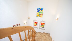 A wooden staircase with a handrail, leading to a landing with three framed artworks on the wall. - Gästehaus Waldesrand (Soelden)