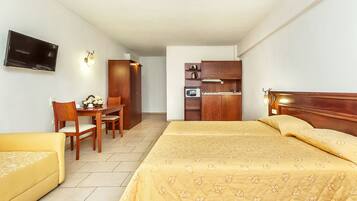 Una habitación de hotel con una cama, un escritorio, una silla, un televisor y un kitchenette.