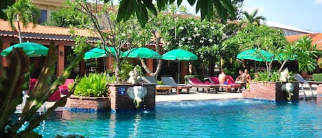 Alberca al aire libre, sombrillas en la alberca y camastros