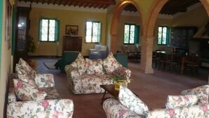 A spacious living room with floral-patterned sofas, a wooden ceiling, and arched doorways. - Caio Alto (Cetona)