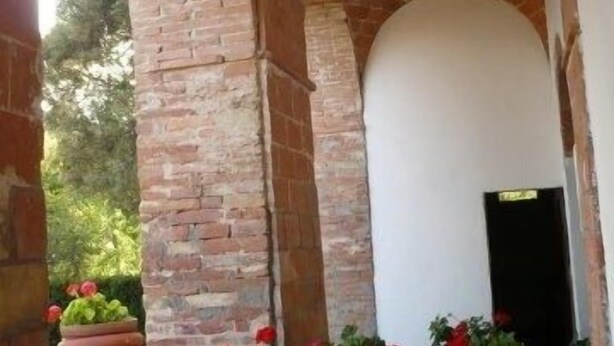 A brick archway with a white wall and a door. - Caio Alto (Cetona)
