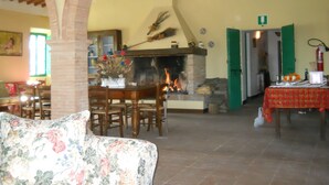 A cozy living room with a fireplace, a dining area, and a green door leading to another room. - Caio Alto (Cetona)
