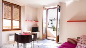 Una habitación con una mesa de comedor, sillas, televisor, sofá y una puerta corrediza de vidrio que da a un área exterior.