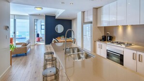 A modern kitchen with a large island, stainless steel appliances, and a view to the living area. - Zara Tower Hotel (Sydney)
