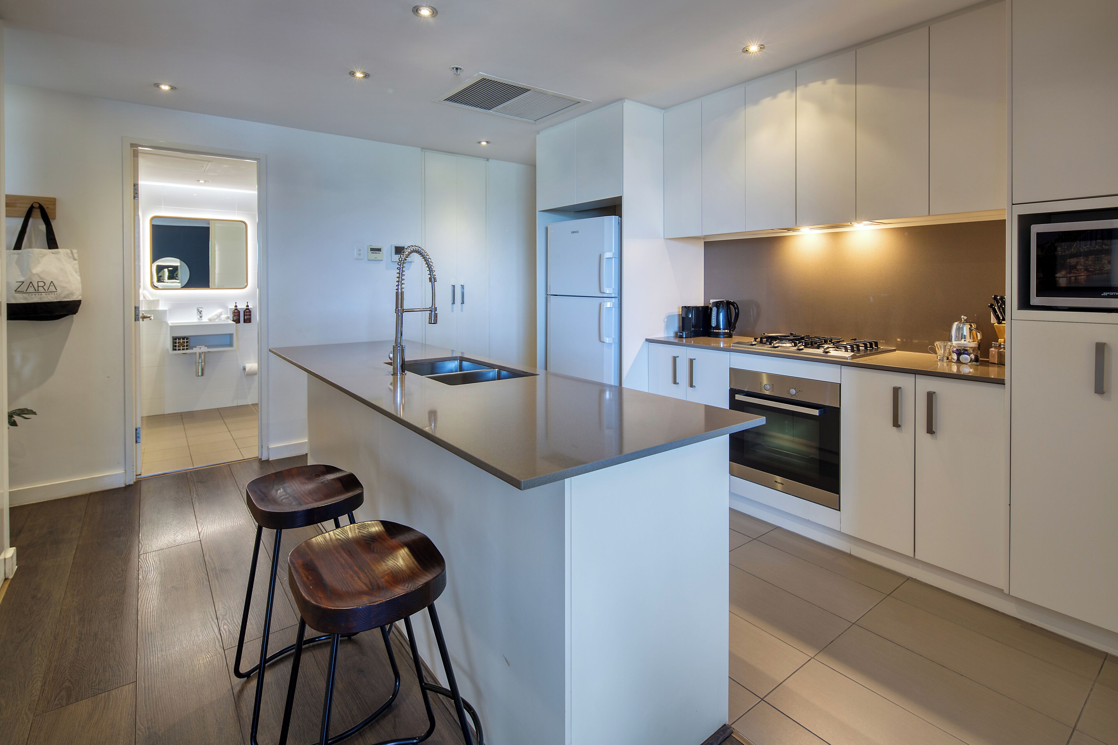 A modern kitchen with a central island, stainless steel appliances, and a bar stool.