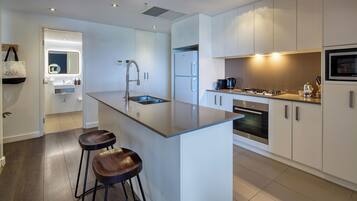 A modern kitchen with a central island, stainless steel appliances, and a bar stool.