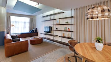 Ein modernes Wohnzimmer mit einer Couch, einem Couchtisch, einem Fernseher und Regalen mit Dekoration.
