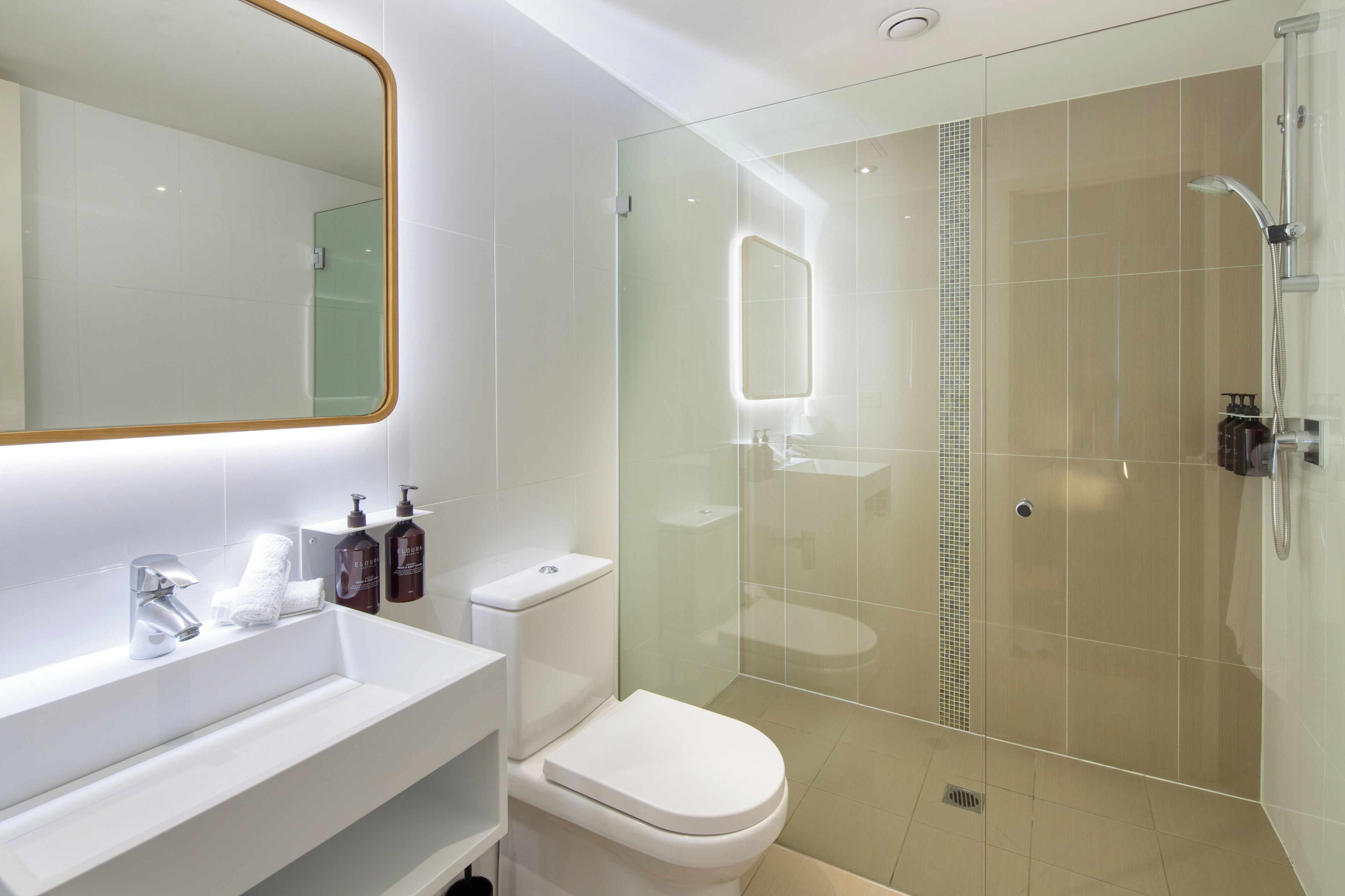 A modern bathroom with a glass-enclosed shower, a white sink, and a toilet.