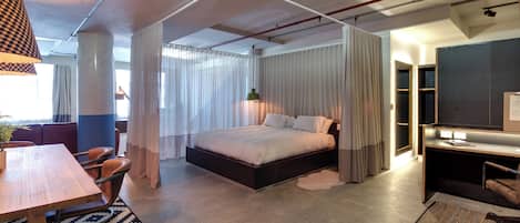 A modern bedroom with a large bed, a desk, and a television.