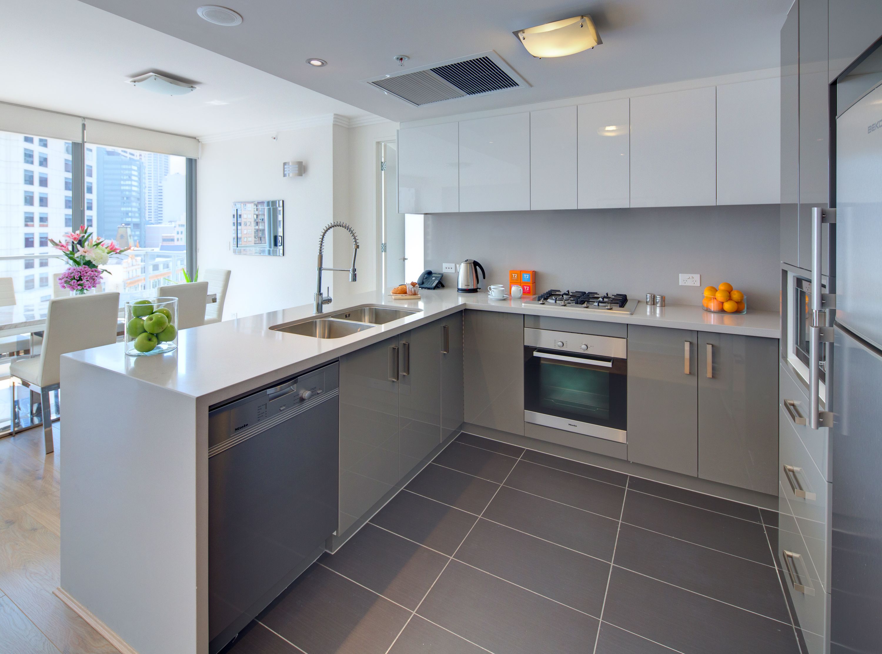 A modern kitchen with stainless steel appliances, a dishwasher, and a large window offering a city view.
