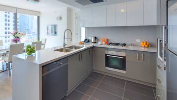 A modern kitchen with stainless steel appliances, a dishwasher, and a large window offering a city view.