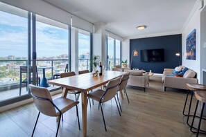 A spacious living area with a dining table, chairs, a sofa, and a TV.