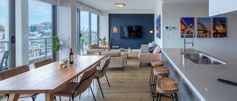 Un espacio moderno para vivir con comedor, cocina y ventanas amplias que ofrecen vistas de la ciudad.
