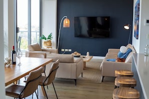 A modern living room with a sofa, a dining table, and a TV mounted on the wall. - Zara Tower Hotel (Sydney)
