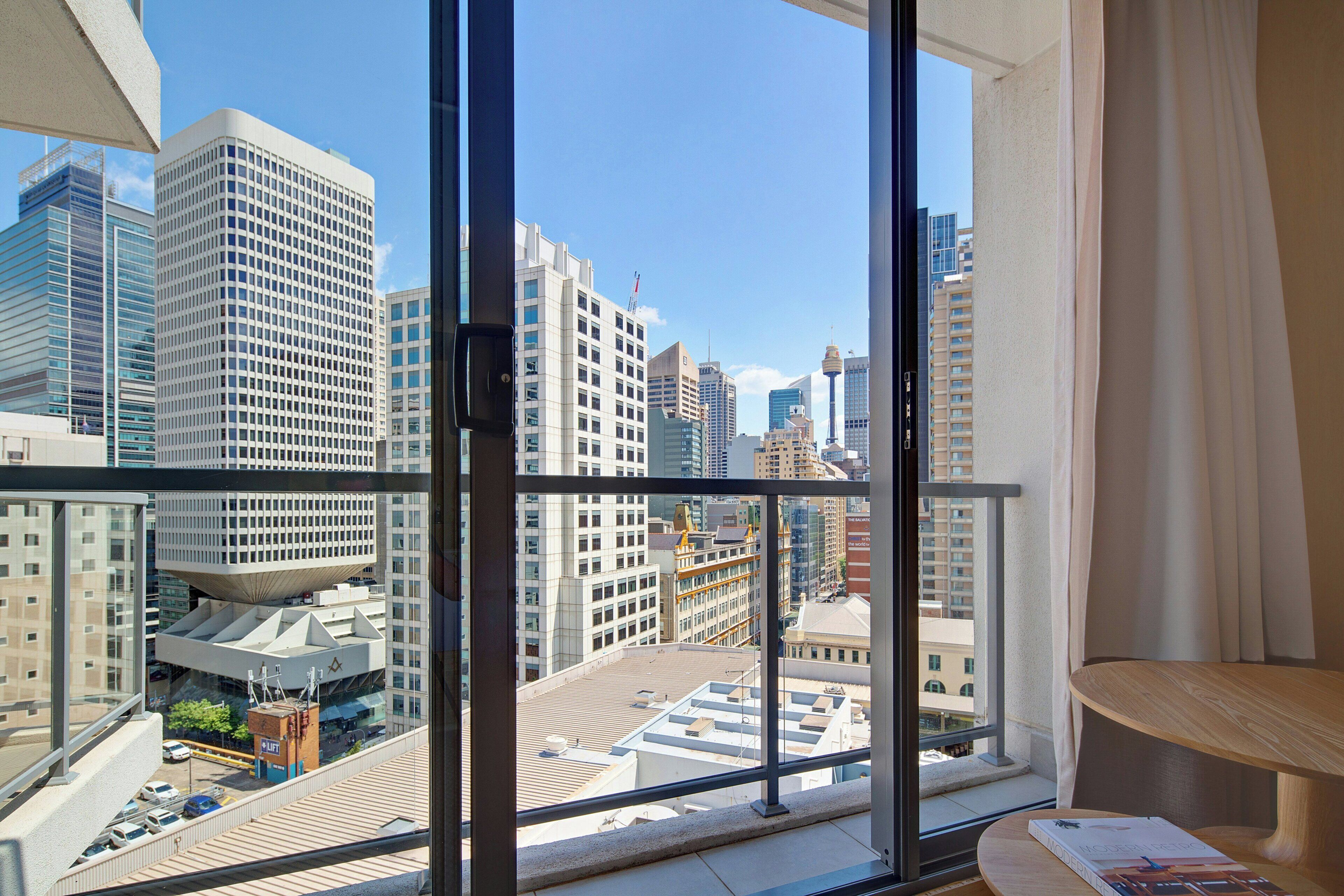 A high-rise hotel room with a large window offering a city view.