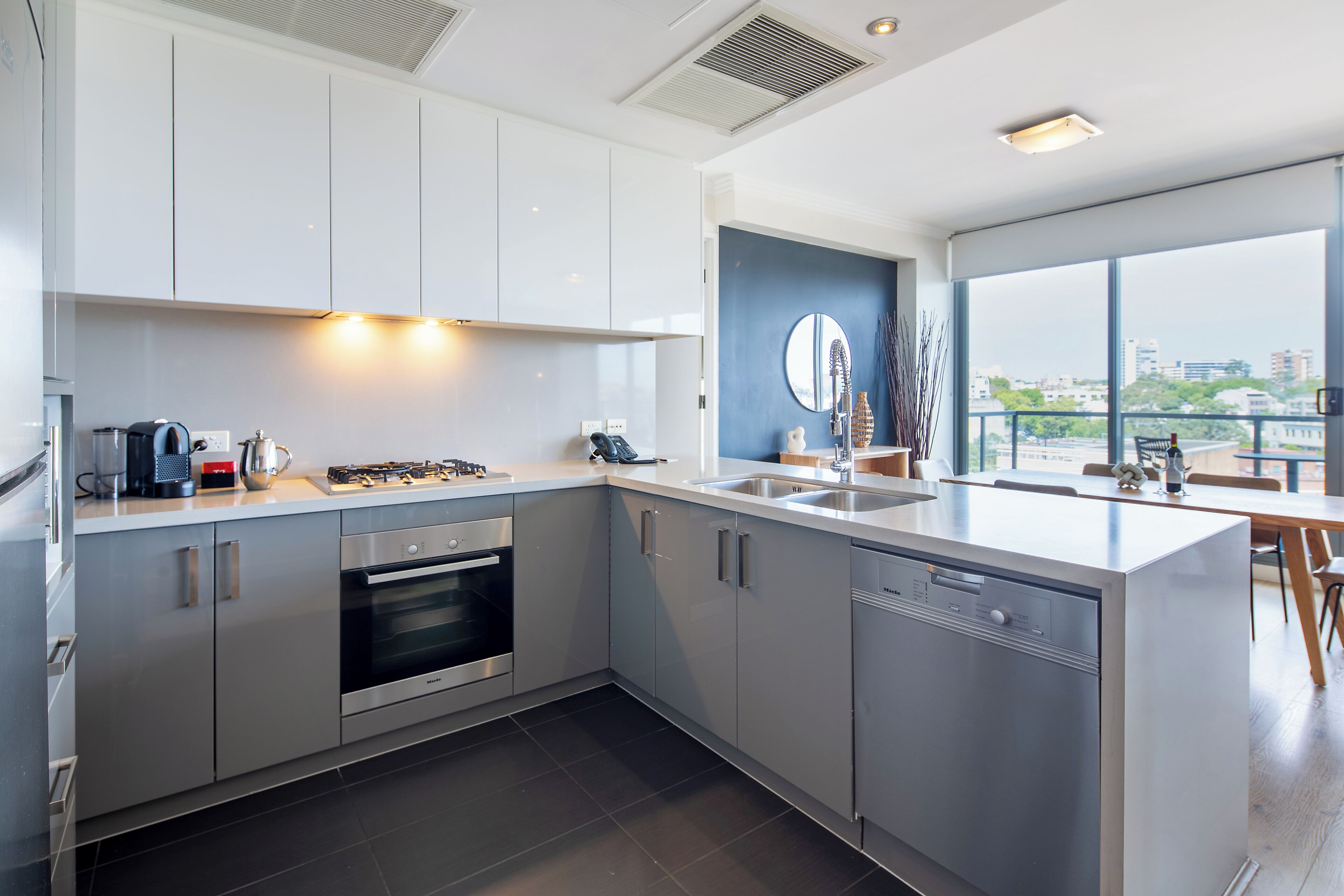 A modern kitchen with stainless steel appliances, a large island, and a view of the city.