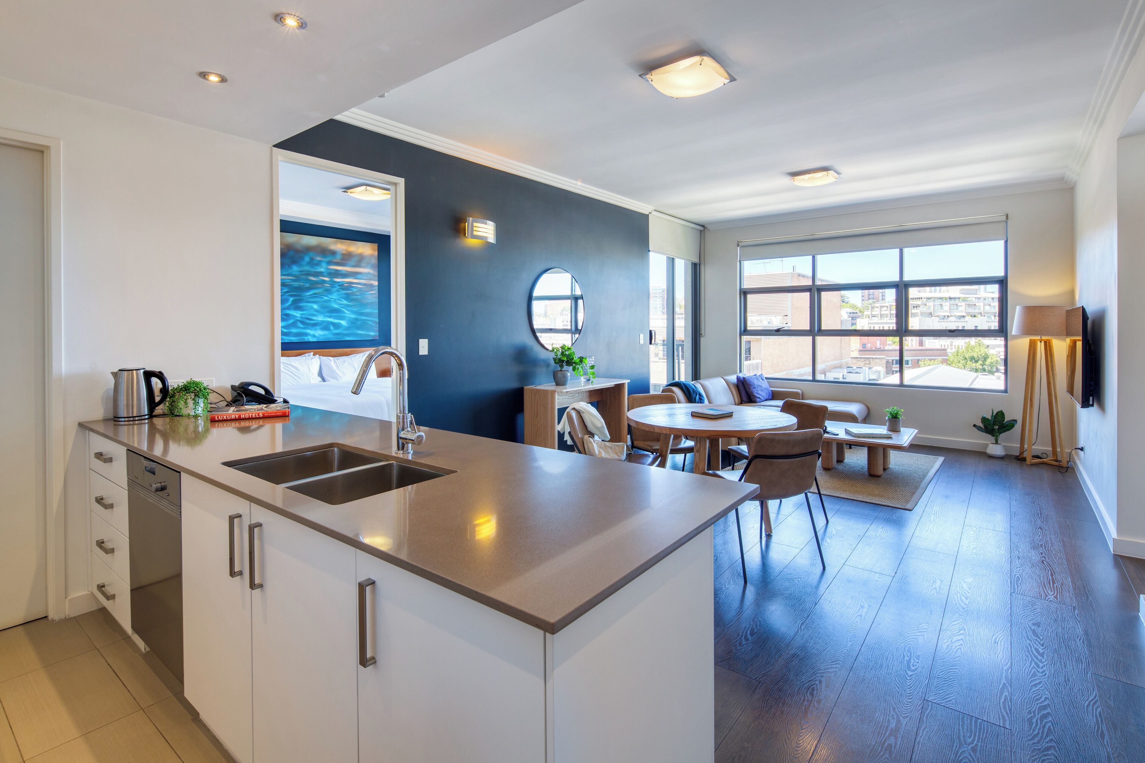 Una cocina moderna con una isla central, un comedor con una mesa redonda y vistas a la ciudad a través de amplios ventanales.