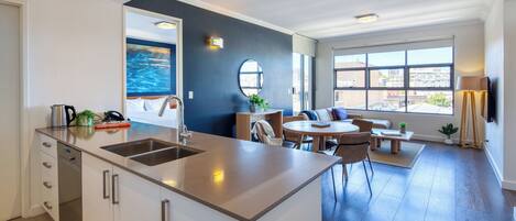 Una cocina moderna con una isla central, un comedor con una mesa redonda y vistas a la ciudad a través de amplios ventanales.
