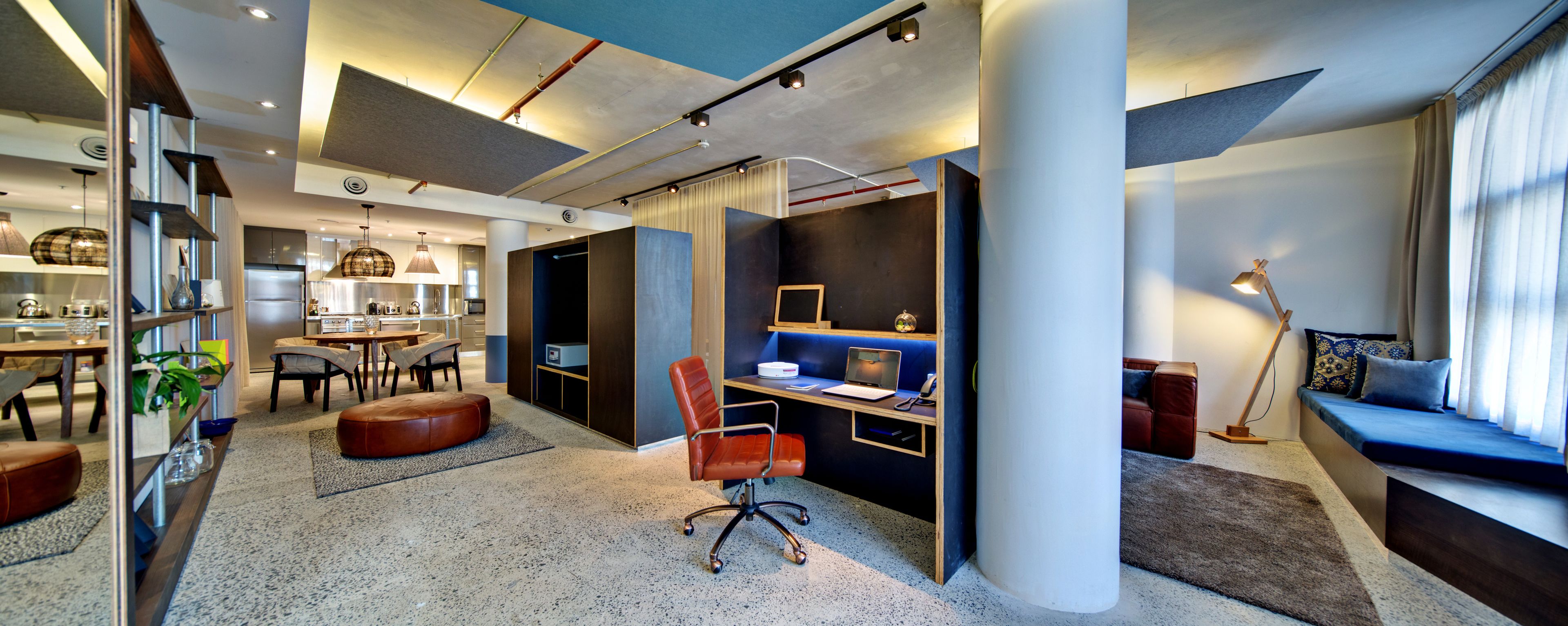 A modern interior with a dining area, kitchen, and a workspace with a desk and chair.