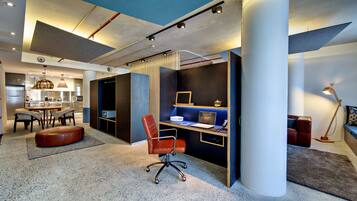 A modern interior with a dining area, kitchen, and a workspace with a desk and chair.