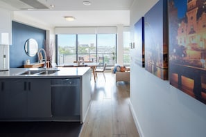 A modern kitchen with a central island, a dining area with a view, and a living space with artwork. - Zara Tower Hotel (Sydney)
