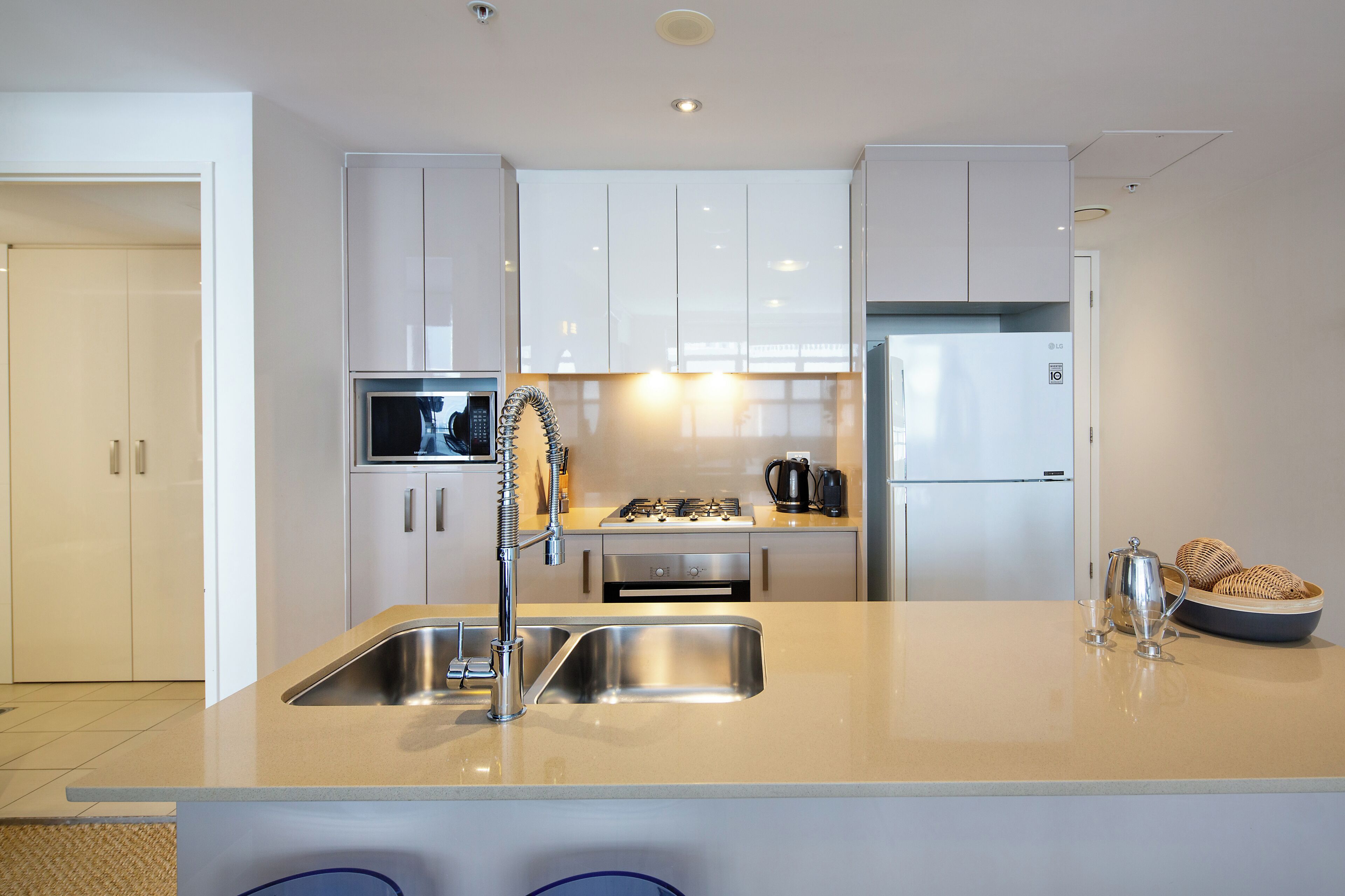 A modern kitchen with a stainless steel sink, a stove, and a refrigerator.