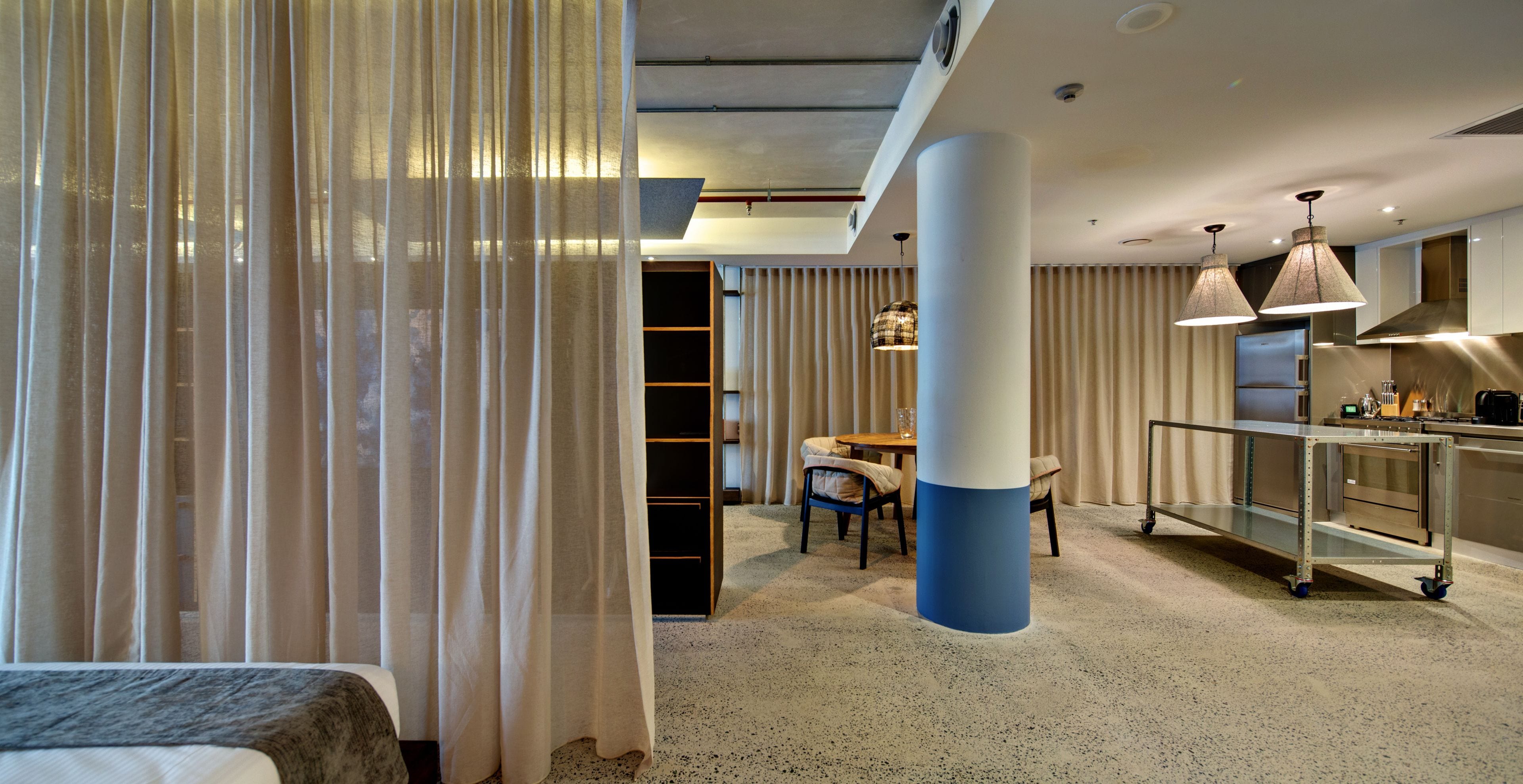 Une chambre d’hôtel moderne comprenant un lit, un coin repas et un coin cuisine.